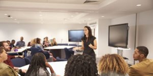 Female teacher addressing university students in a classroom