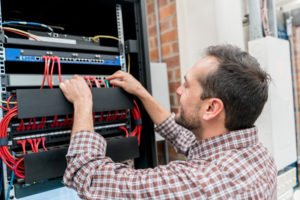 IT technician fixing cables at the office - technology concepts